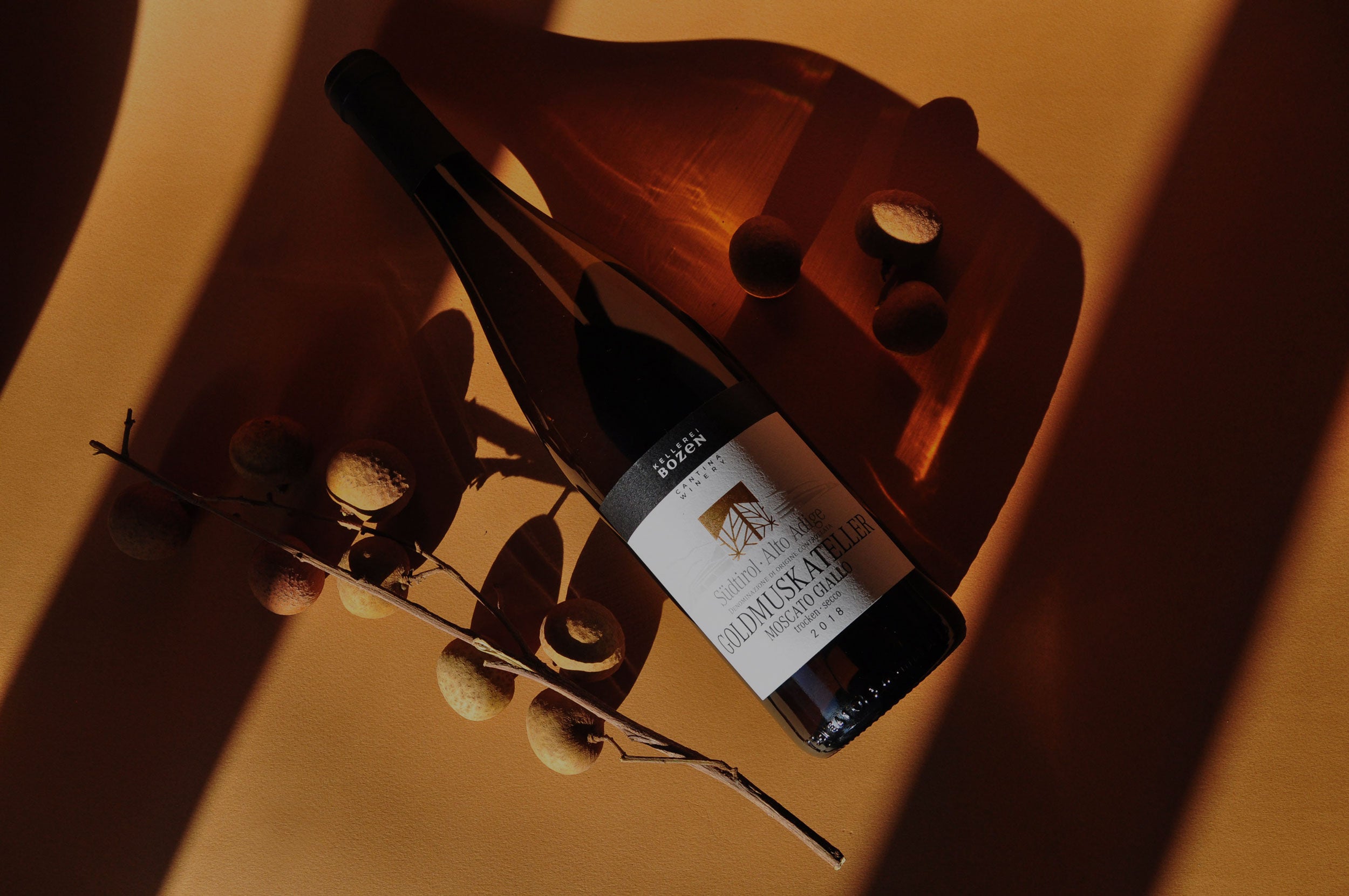 Styled image of Kellerei Bozen Goldmuskateller with fresh fruits — a fragrant, organic white wine from Alto Adige known for its aromatic intensity and natural sweetness