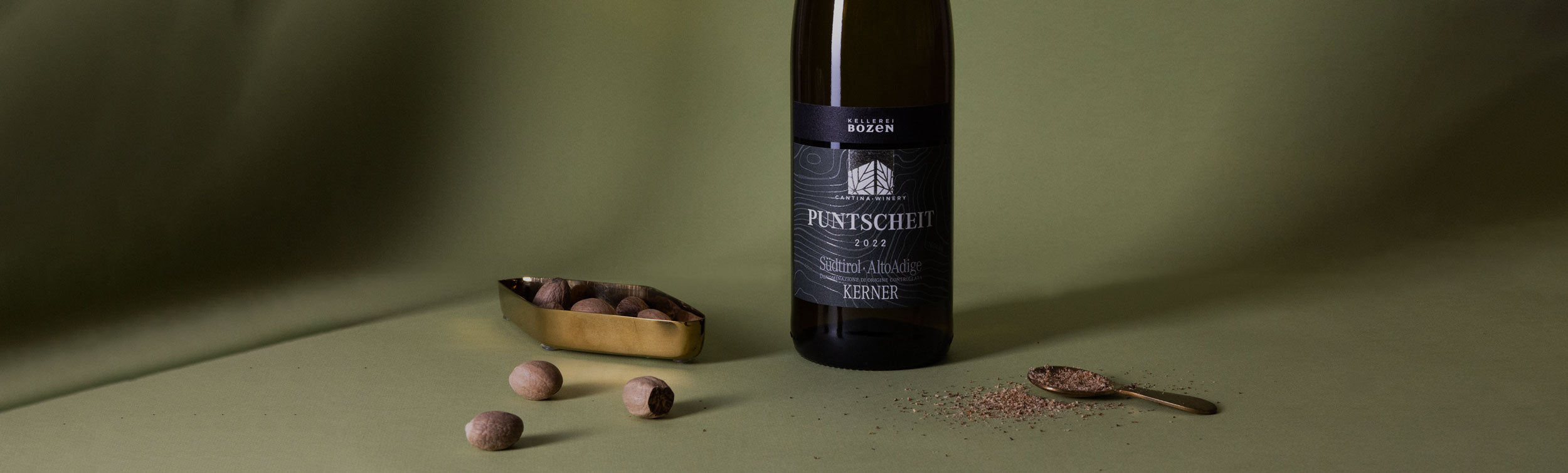 Styled image of Kellerei Bozen Kerner white wine beside aromatic spices — showcasing the Alpine freshness and spice-driven character of this South Tyrolean wine